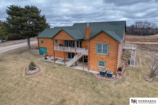 back of house with central AC unit, a lawn, and a patio