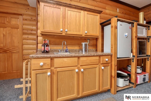 kitchen featuring sink, light colored carpet, and log walls