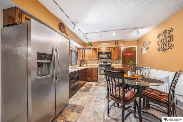 kitchen featuring black appliances, stone finish floor, a sink, backsplash, and light countertops