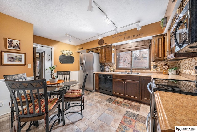 kitchen with backsplash, black appliances, light countertops, a textured ceiling, and a sink