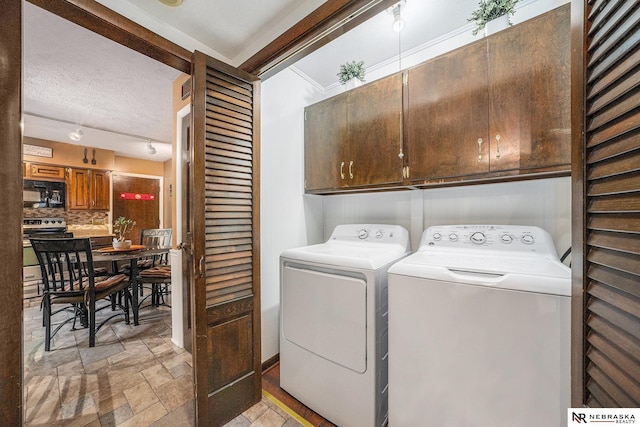 laundry area with cabinet space, a textured ceiling, stone tile flooring, and washing machine and clothes dryer