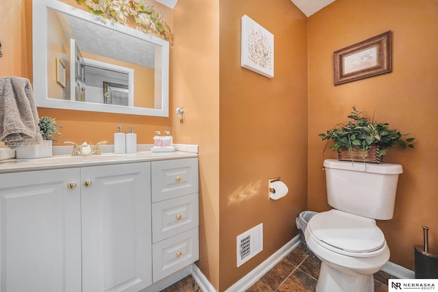 bathroom with vanity, toilet, baseboards, and visible vents