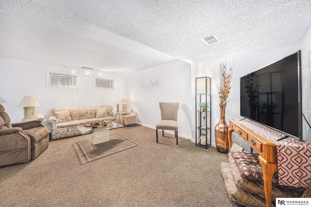 carpeted living room featuring rail lighting, baseboards, visible vents, and a textured ceiling