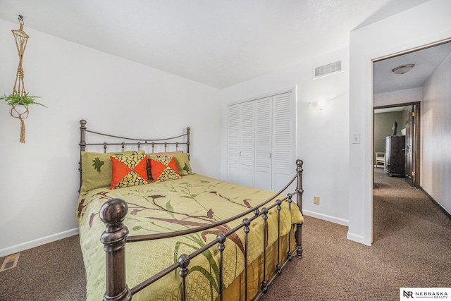 bedroom with a closet, visible vents, dark carpet, and baseboards