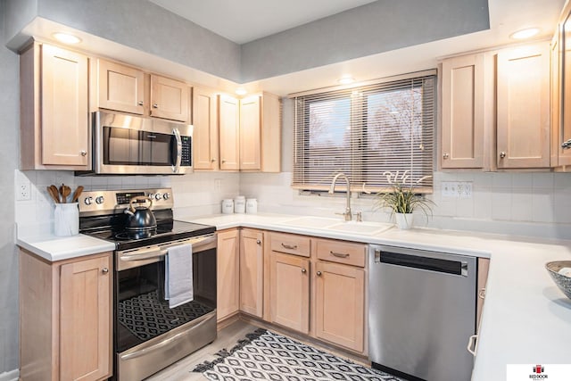 kitchen with tasteful backsplash, appliances with stainless steel finishes, light brown cabinetry, and sink