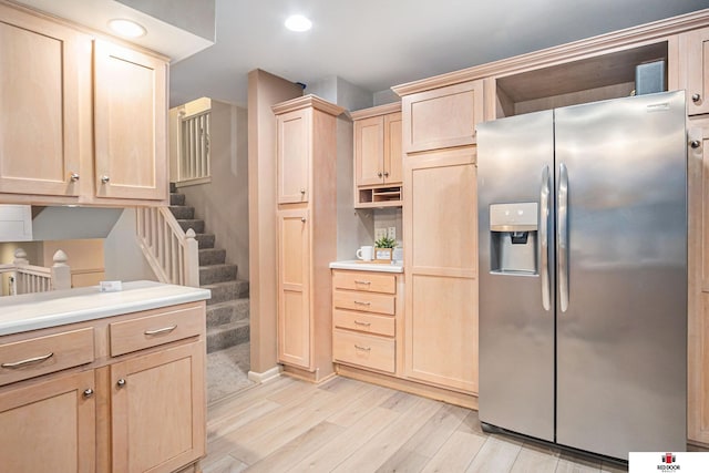 kitchen with stainless steel refrigerator with ice dispenser, light wood-type flooring, and light brown cabinets