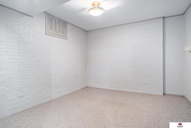 carpeted spare room with brick wall