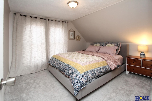 bedroom featuring carpet flooring, vaulted ceiling, and a textured ceiling