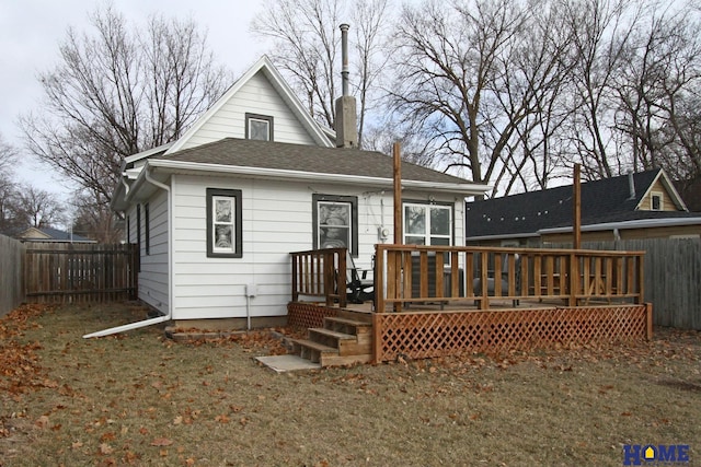 back of property featuring a deck and a lawn