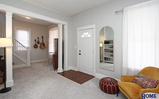 entryway with carpet floors and decorative columns