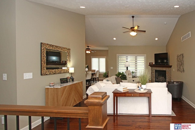 living room featuring lofted ceiling, ceiling fan, dark wood-type flooring, and a textured ceiling