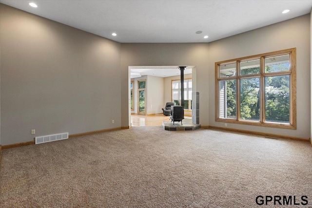 unfurnished living room featuring carpet floors and a wood stove