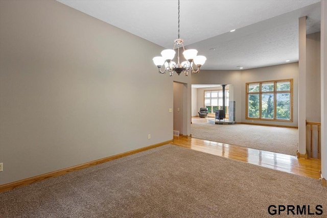 carpeted spare room with a notable chandelier and a textured ceiling