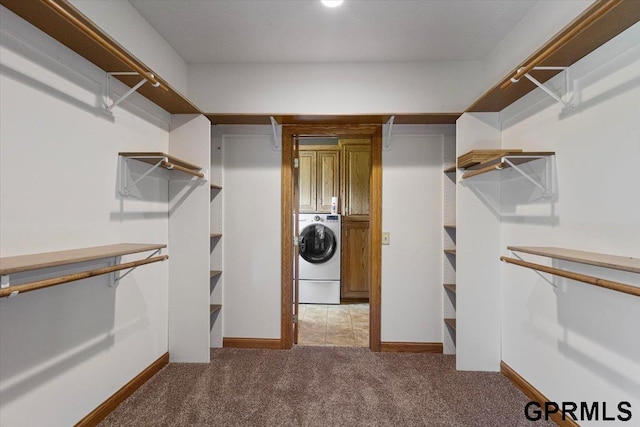 spacious closet featuring washer / dryer and light colored carpet