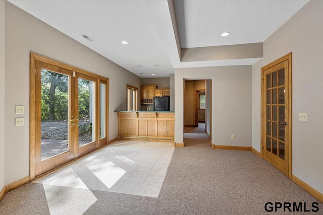 unfurnished living room featuring light colored carpet and french doors