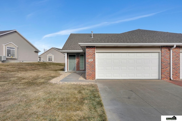 view of front of property featuring a garage, central AC, and a front yard