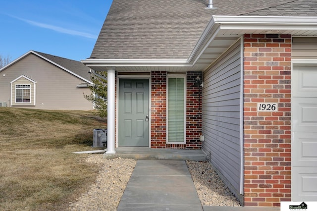 view of exterior entry featuring cooling unit, a yard, and a garage