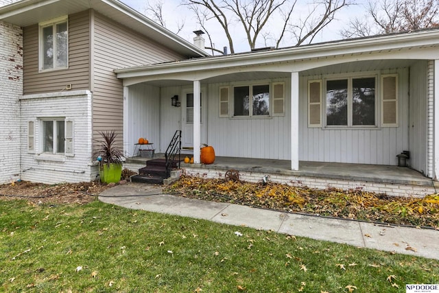 doorway to property featuring a porch and a yard