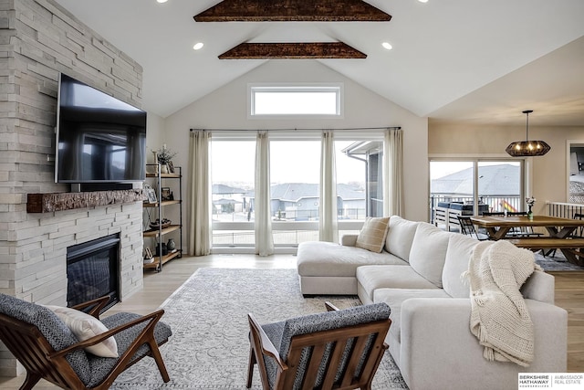 living room featuring lofted ceiling with beams, a stone fireplace, and light hardwood / wood-style floors