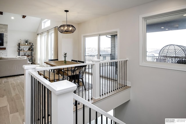 interior space featuring an inviting chandelier, vaulted ceiling, and light wood-type flooring