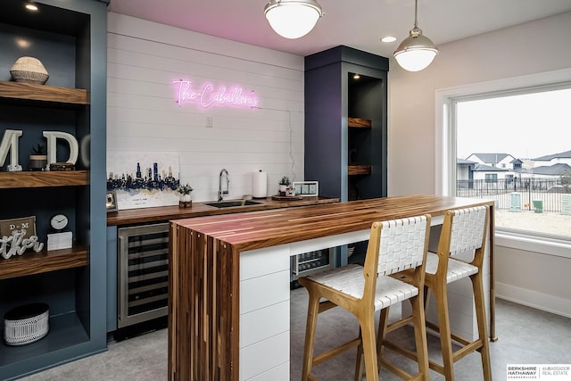 bar featuring butcher block counters, sink, wine cooler, and decorative light fixtures