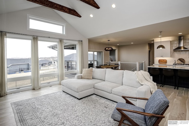 living room with high vaulted ceiling, beamed ceiling, and light wood-type flooring