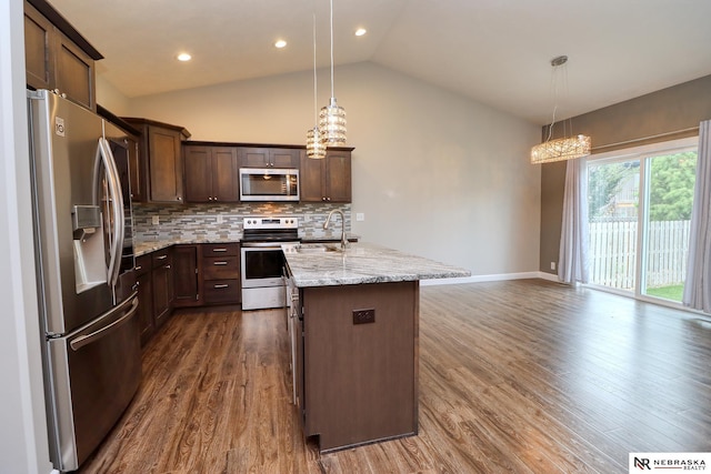 kitchen featuring a kitchen island with sink, sink, decorative light fixtures, and appliances with stainless steel finishes