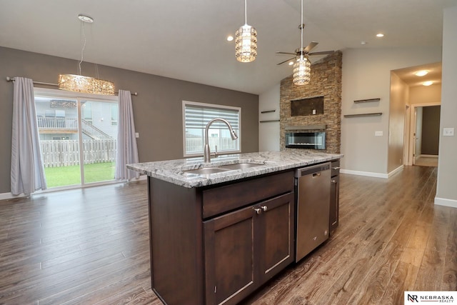 kitchen featuring dark brown cabinetry, lofted ceiling, sink, light stone counters, and stainless steel dishwasher