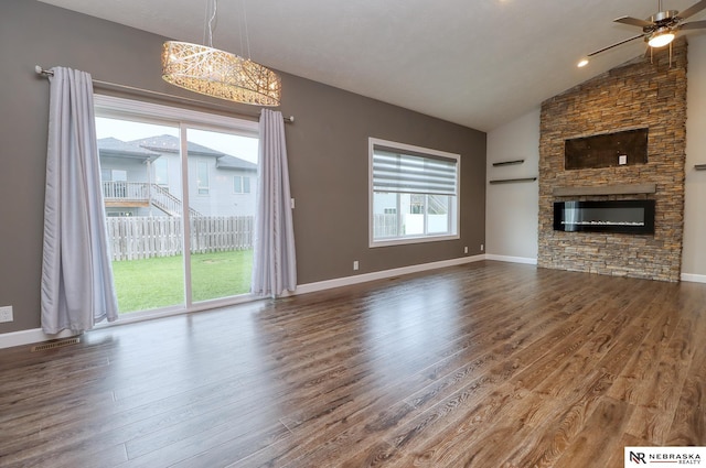 unfurnished living room featuring ceiling fan with notable chandelier, lofted ceiling, a fireplace, and hardwood / wood-style floors