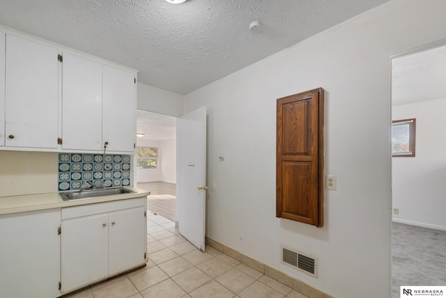 kitchen with white cabinetry, sink, a textured ceiling, and light tile patterned flooring