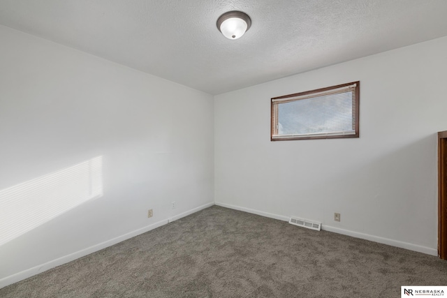 carpeted empty room featuring a textured ceiling