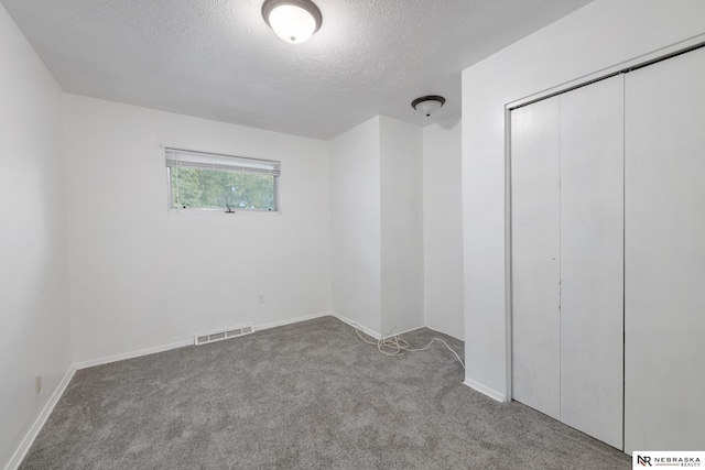 unfurnished bedroom with a closet, a textured ceiling, and carpet