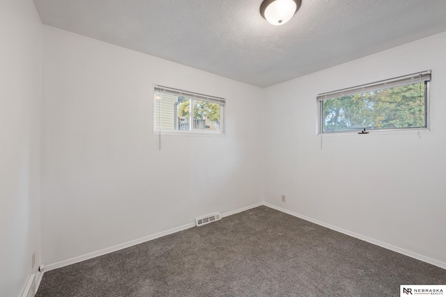 empty room with dark carpet and a textured ceiling