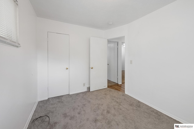 unfurnished bedroom with a closet and light carpet