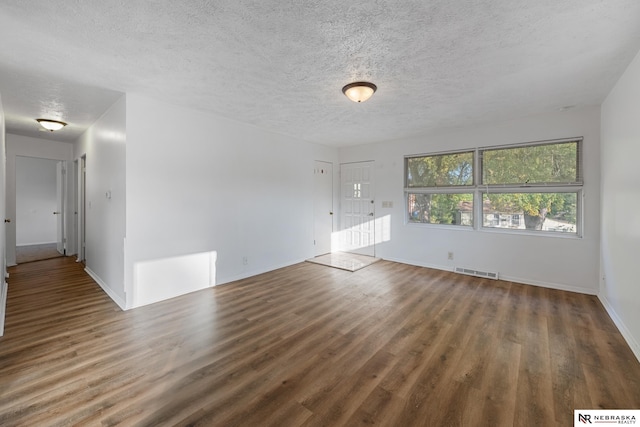 unfurnished living room featuring a textured ceiling and dark hardwood / wood-style flooring