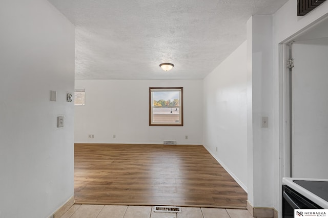 spare room with light hardwood / wood-style floors and a textured ceiling