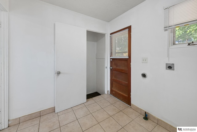 laundry area with light tile patterned flooring, hookup for an electric dryer, and a textured ceiling