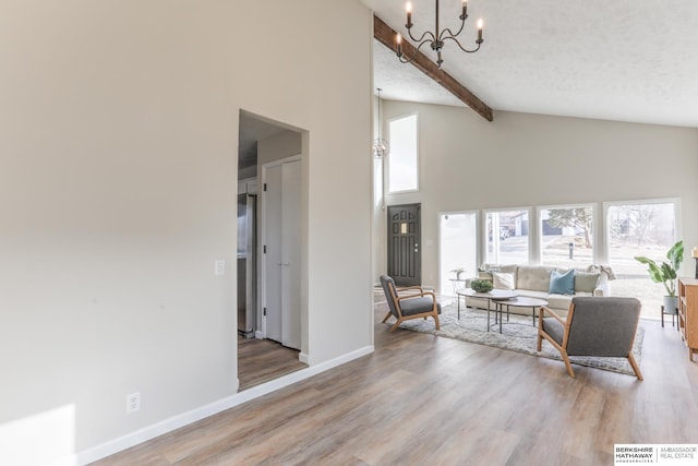 living room featuring a notable chandelier, beam ceiling, light hardwood / wood-style flooring, and a textured ceiling