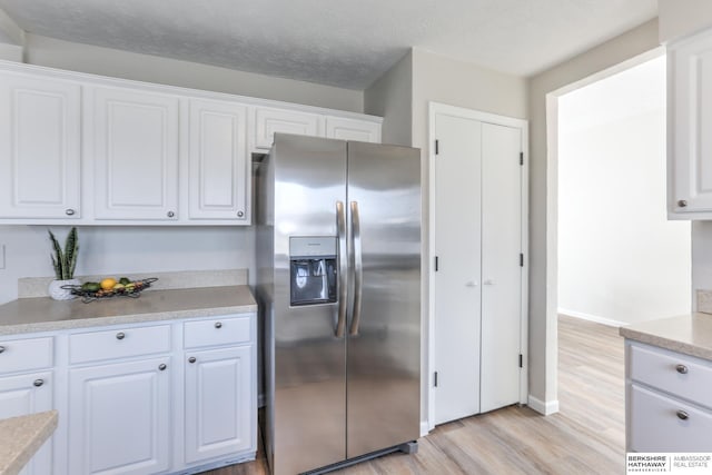 kitchen with white cabinetry, stainless steel fridge with ice dispenser, light hardwood / wood-style floors, and a textured ceiling