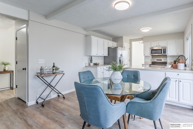 dining room featuring beam ceiling and light hardwood / wood-style flooring