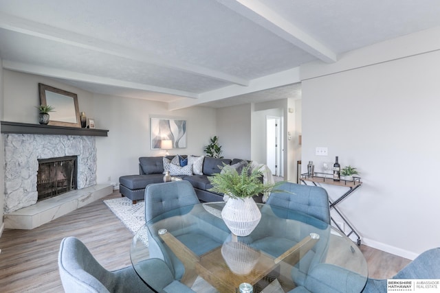 living room featuring a fireplace, beam ceiling, and light hardwood / wood-style floors