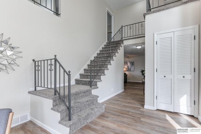 stairs with wood-type flooring and a high ceiling