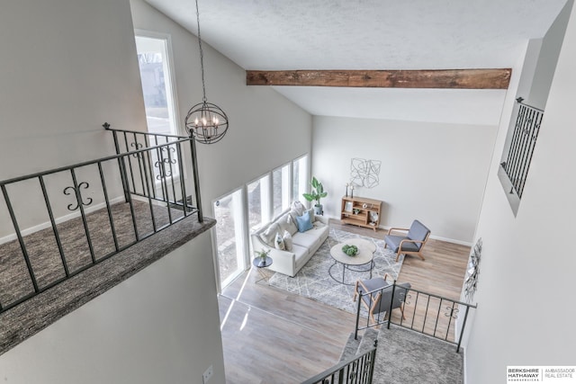 living room featuring lofted ceiling with beams, hardwood / wood-style floors, and a notable chandelier