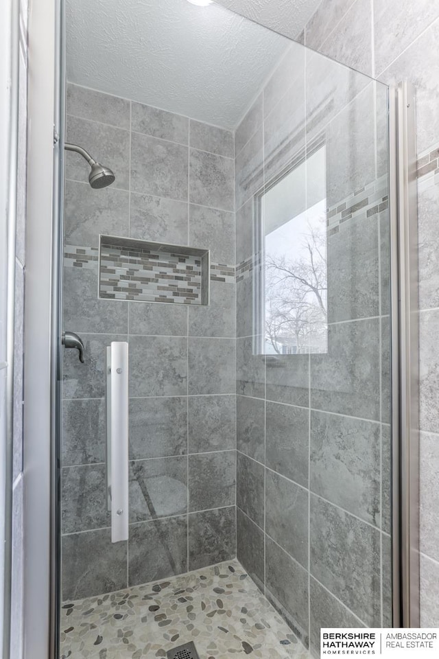 bathroom with tiled shower and a textured ceiling