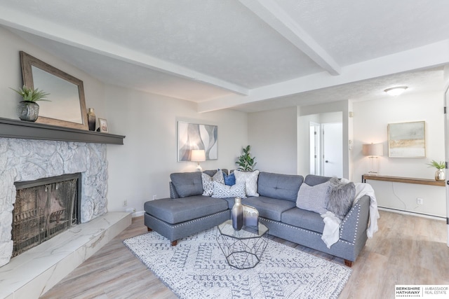 living room featuring beamed ceiling, a fireplace, and light wood-type flooring