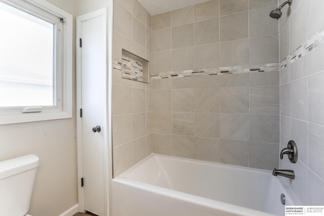 bathroom with toilet and tiled shower / bath