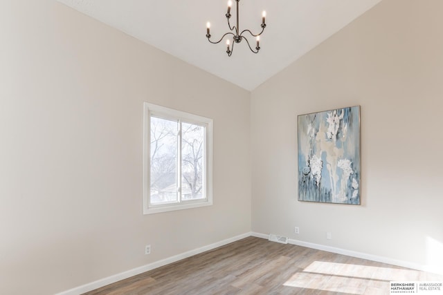 unfurnished room with an inviting chandelier, light hardwood / wood-style floors, and vaulted ceiling