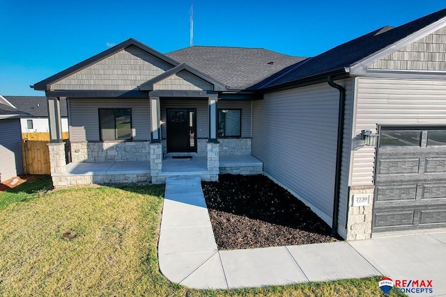 view of front of property featuring a garage, a front yard, and covered porch