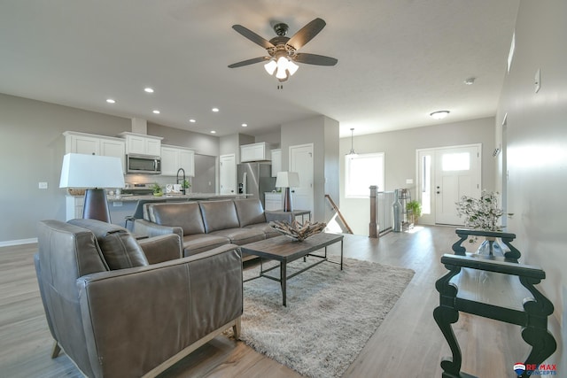 living room featuring ceiling fan, sink, and light hardwood / wood-style flooring