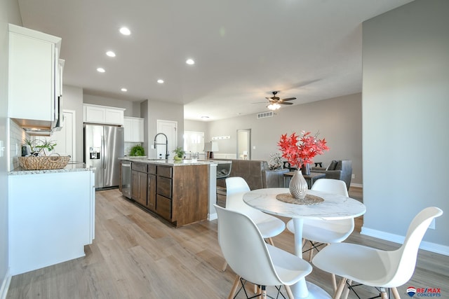 dining space with ceiling fan, sink, and light hardwood / wood-style floors